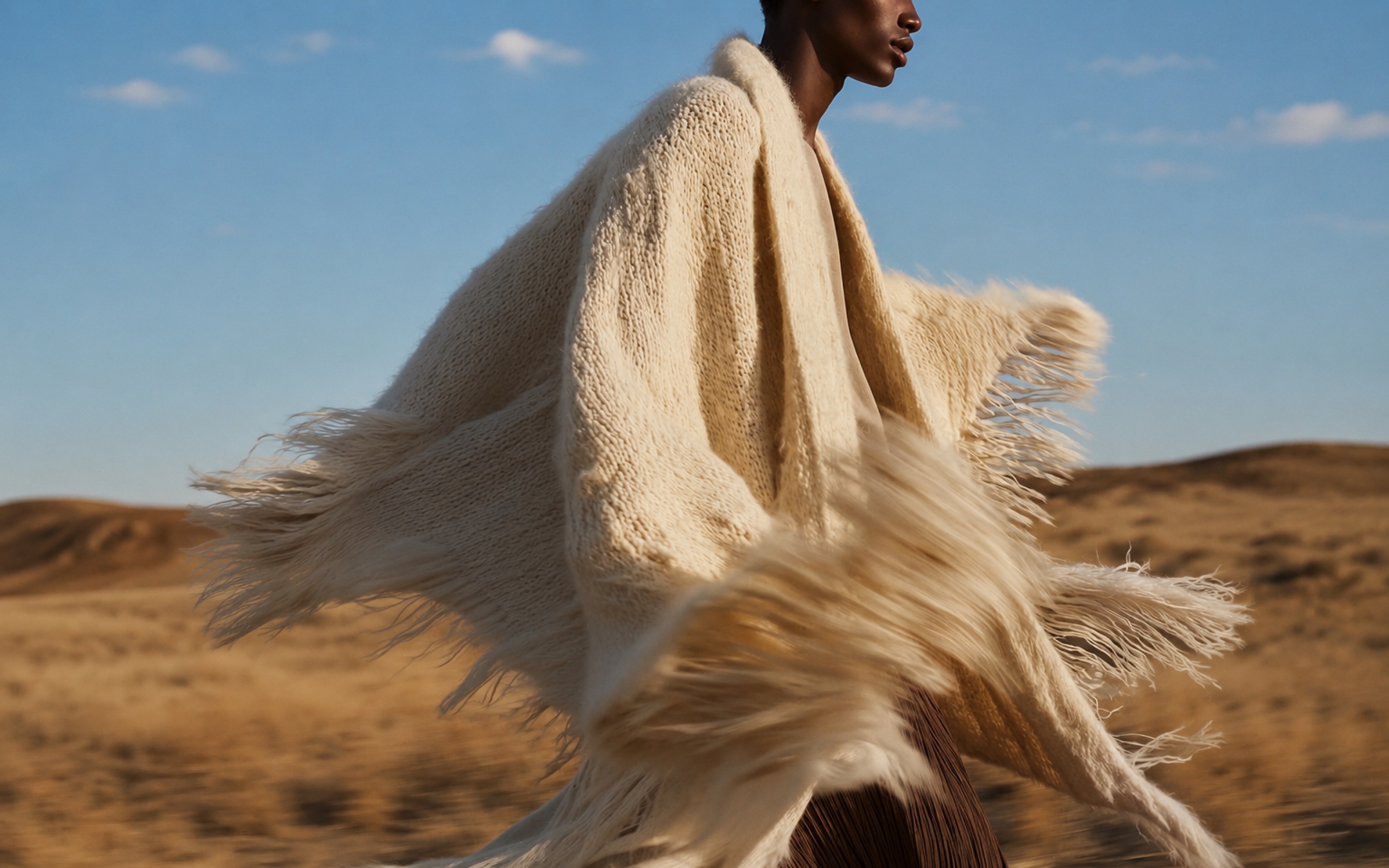 A person in a cream alpaca wrap standing in a desert