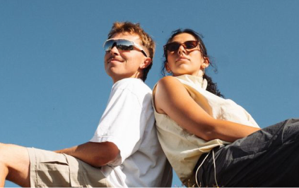 Two people sitting back to back under a clear sky