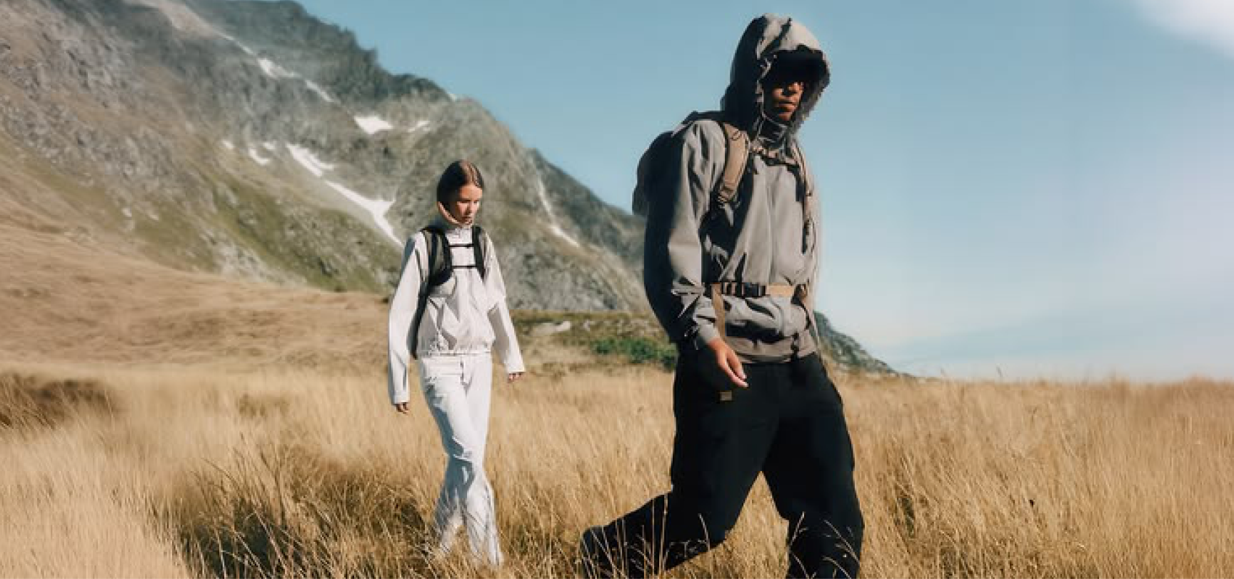 Two people walking through a mountain meadow