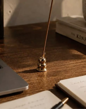 A brass incense holder on a wooden desk